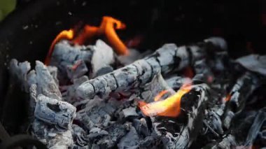 Kara odun ve kömürde alevler yanıp sönüyor..