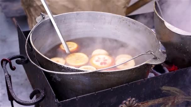 Closeup ορεκτικές mulled κρασί με πορτοκάλια, ψημένα σε ψησταριά με κάρβουνα σε εξωτερικούς χώρους — Αρχείο Βίντεο