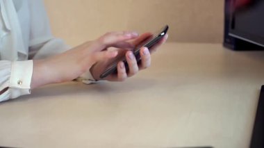 Apps kullanan smartphone işyerinde kontrol, yazarak, kaydırma, zarif kadın
