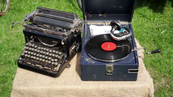 Vintage vinyl record player and old manual typewriter displayed outdoors — Stock Video
