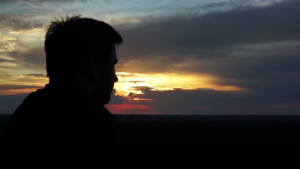 Silueta masculina al atardecer, hombre mirando al cielo, pensando en la vida, recuerdos — Vídeos de Stock