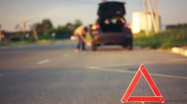 Yol kenarında, kırmızı uyarı üçgen işareti, sürücü değişen düz lastik kırık araba