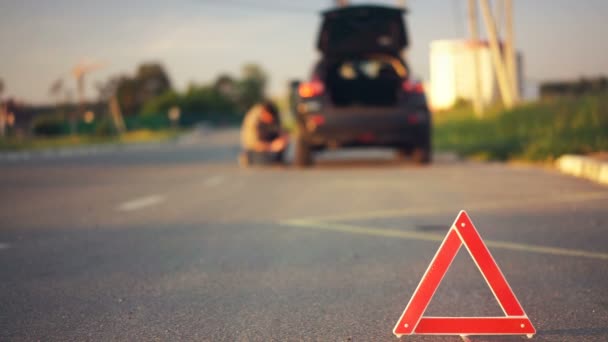 Road hazard triangle on road, unlucky driver changing flat tyre, car breakdown — Stock Video