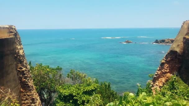 Endless blue ocean under clear sky, rocky cliffs above calm transparent water — Stock Video