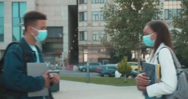 Maskeli okul arkadaşları dirseklerini vuruyor, sokakta buluşuyorlar, sosyal uzaklık...