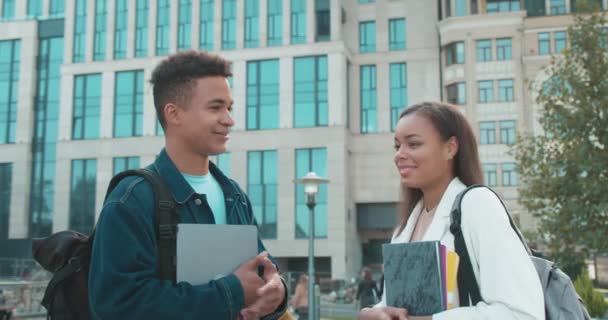 Estudantes universitários discutindo aulas ao ar livre, segurando cadernos, comunicação — Vídeo de Stock