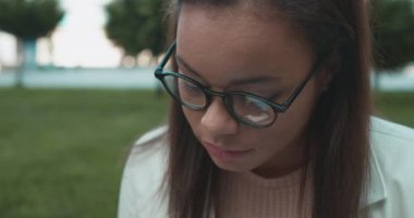 Gözlüklü bayan üniversite öğrencisi park ve üniversite sınavlarına hazırlanıyor.
