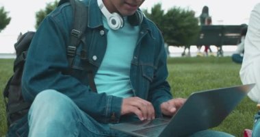 Modern öğrenci, kampüsteki çimlerin üzerinde oturan bilgisayar dokümanları, teknoloji