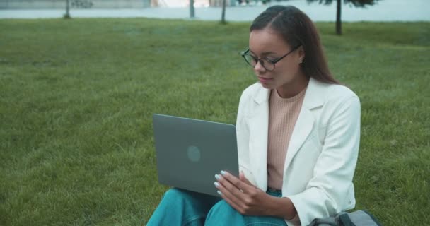 Mulher mista feliz fechando laptop, sentado no parque, fim do projeto, sucesso — Vídeo de Stock