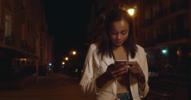 Gülümseyen öğrenci akıllı telefondan fotoğraf çekiyor, arkadaşını bekliyor, teknoloji...