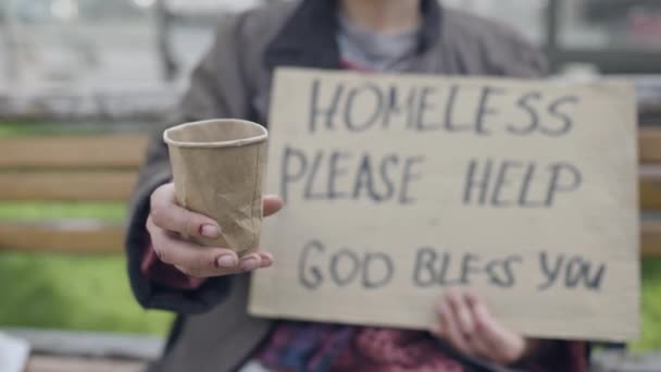 Бедный нищий держит бумажную чашку, незнакомец жертвует монеты нуждающейся женщине, помогает — стоковое видео