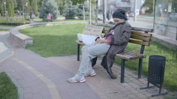 Pijana bezdomna kobieta z butelką w ręku śpiąca na ławce, nadużywanie alkoholu — Wideo stockowe