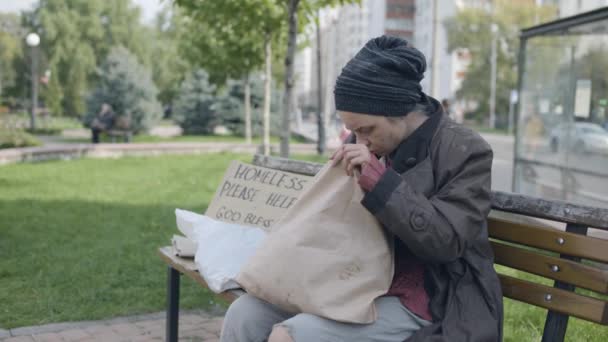 Dışarıda ekmek yiyen aç bir serseri, sokakta yaşayan yalnız bir genç. — Stok video