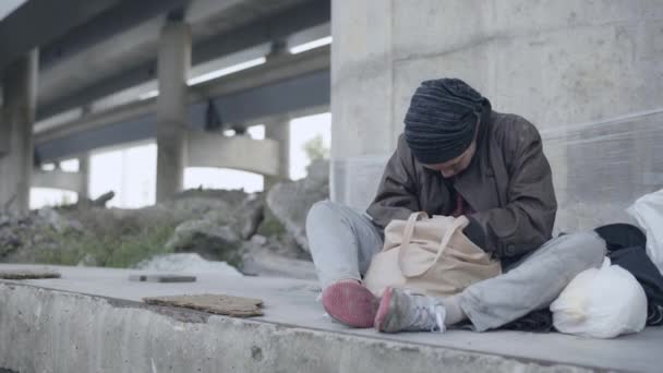 Wanhopige vrouwelijke zwerver bijtend brood, overleven op straat, economische crisis — Stockvideo