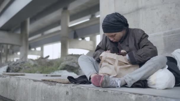 Fattiga invandrare äter bröd, sitter på marken, social utsatthet, förtvivlan — Stockvideo
