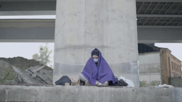Άστεγη γυναίκα με προστατευτική μάσκα που βήχει, κάθεται στο έδαφος, ιός. — Αρχείο Βίντεο