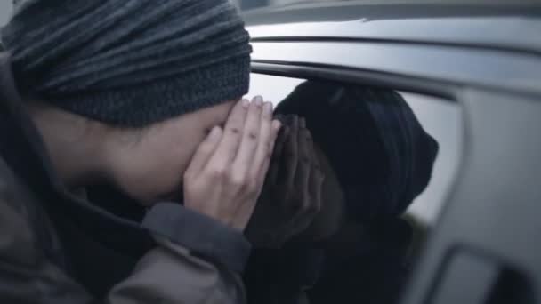 Dakloze vrouw kijkt in auto door glas, op zoek naar geld en voedsel — Stockvideo