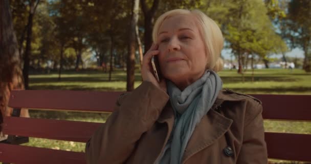 Mujer alegre hablando por teléfono en el parque, jubilado activo saludable, conversación — Vídeos de Stock
