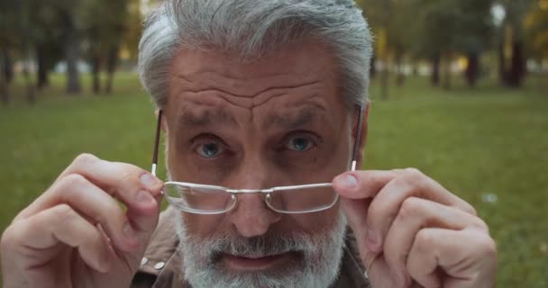 Hombre canoso mirando a la cámara a través de anteojos, elección de lentes, cataratas — Vídeos de Stock