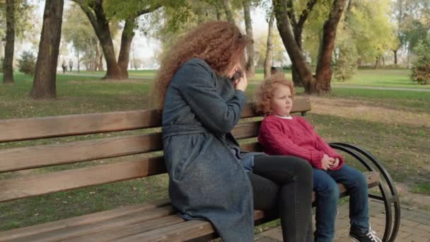 Mujer pelirroja hablando con un niño pequeño en el parque, acercándose a los niños, adopción — Vídeos de Stock