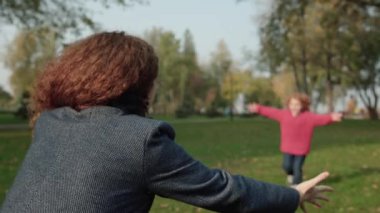 Neşeli oğul parkta annesine sarılıyor, ebeveynleriyle iletişim kuruyor, olumlu duygular besliyor.
