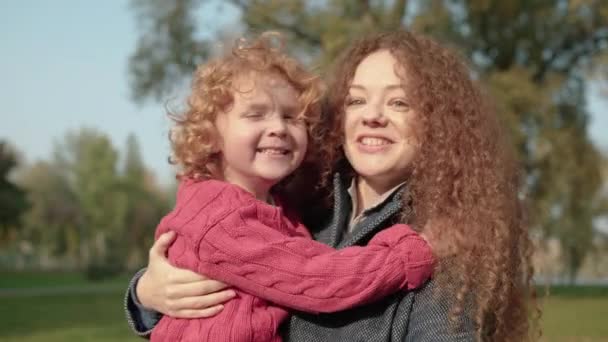 Красивая рыжая мать держит очаровательного сына, проводит время вместе, весело — стоковое видео