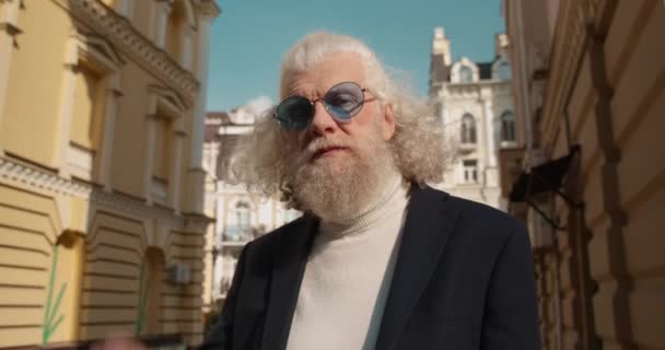 Hipster viejo hombre tomando gafas de sol de moda y guiño en la cámara al aire libre estilo — Vídeos de Stock