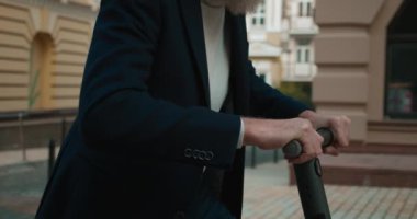 Moda düşkünü yaşlı bir adam elektrikli scooter kullanıyor, çevre dostu bir araç.