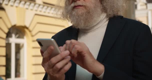 Barbudo viejo hombre desplazándose teléfono inteligente y riendo, charlando en línea, aplicación móvil — Vídeos de Stock