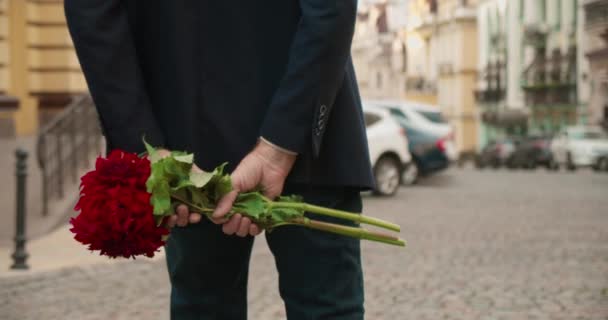 Mâini de sex masculin care țin buchet de flori roșii în spate, bărbat care așteaptă prietena — Videoclip de stoc