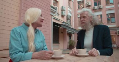 Restoran terasında konuşan ve kahve içen son sınıf mutlu çift.