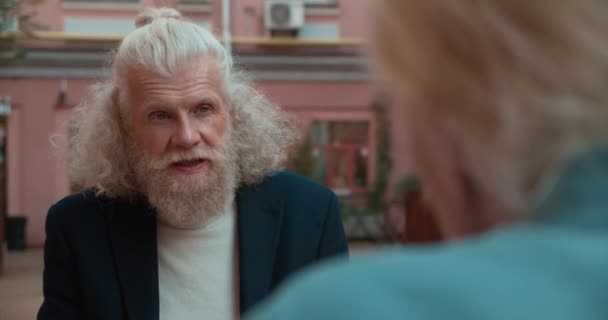 Anciano hipster hombre con barba hablando con un amigo en la cafetería al aire libre, confianza — Vídeo de stock