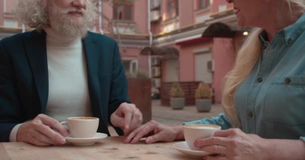 Sakallı yaşlı adam karısının elini okşuyor, kafede kahve içiyor. — Stok video