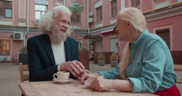 Hipster senior man zoenen liefdevolle vrouw de hand tijdens koffie-break in cafe — Stockvideo