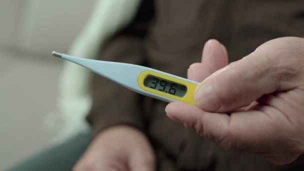 Åldrad man som håller termometer, visar 39 grader, influensasymtom, hälsovård — Stockvideo