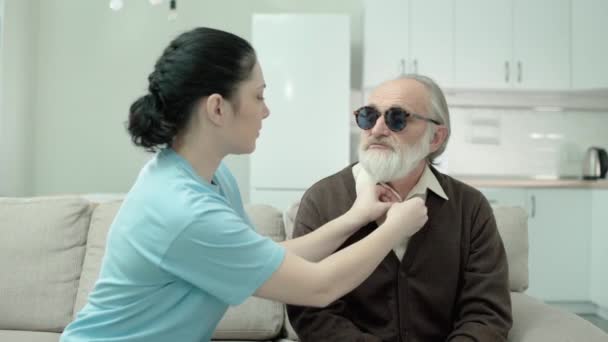 Cuidador ajudando aposentado cego para se vestir, projeto de caridade, altruísmo — Vídeo de Stock