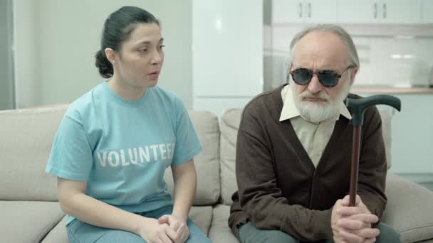 Dobrovolník mluví se smutným slepcem, pomáhá zdravotně postižené osobě, zrakové postižení — Stock video