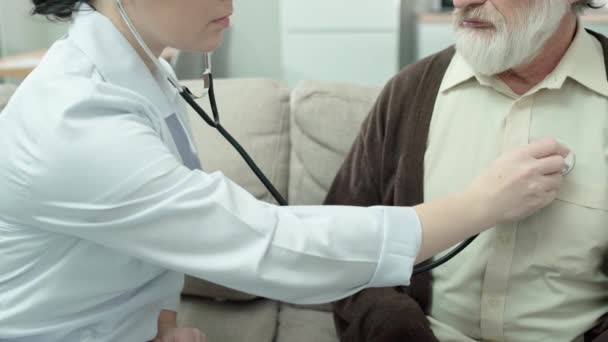 Médico femenino escuchando ruidos respiratorios, examinando los pulmones del hombre, neumonía — Vídeo de stock