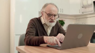 Kafası karışmış yaşlı adam dizüstü bilgisayarda yazmaya çalışıyor, evde oturuyor, son sınıf öğrencisi.