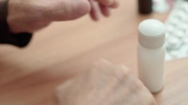 Yaşlı erkek, ilaç şişesi açıyor, evde reçeteli ilaç alıyor, sağlık sorunları var.