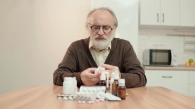 Masadaki ilaç şişelerine bakan kafası karışmış yaşlı adam, antibiyotik terapisi...