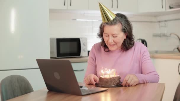 Sonriendo abuela soplando velas de cumpleaños, comunicándose con la familia en línea — Vídeos de Stock