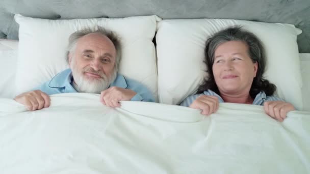 Feliz casal maduro deitado na cama, cobrindo com cobertor, relacionamento romântico — Vídeo de Stock
