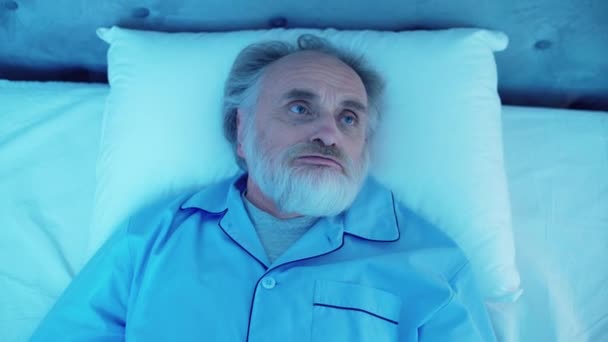 Zdenerwowany starszy mężczyzna leżący w łóżku, próbujący odpocząć z hałasem, bez snu — Wideo stockowe