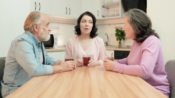 Paar gepensioneerden troosten zielige dochter, zitten samen in de keuken, zorg — Stockvideo