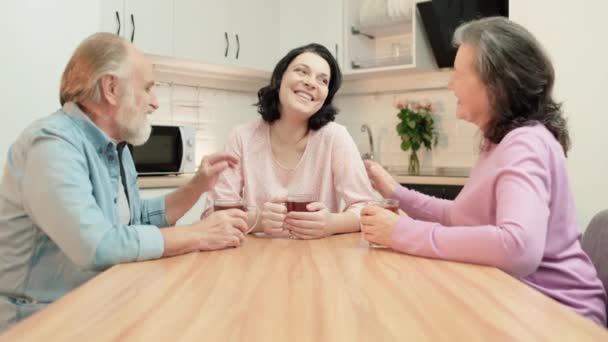 Liebevolle alte Eltern, die mit ihrer Tochter reden, zu Hause Nachrichten besprechen, Tee trinken — Stockvideo