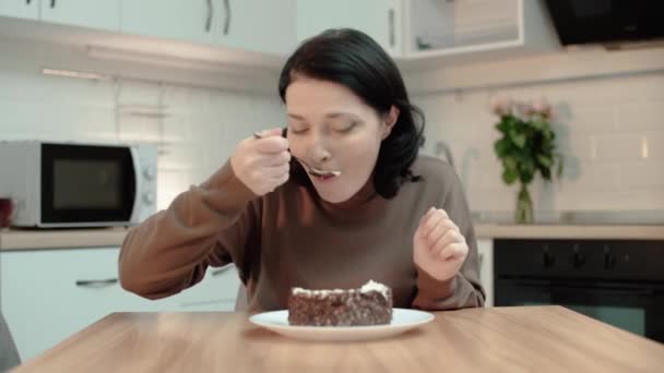 Στρεσαρισμένη μελαχρινή γυναίκα τρώει γλυκό κέικ στο σπίτι, σπάζοντας τη διατροφή, βουλιμία — Αρχείο Βίντεο