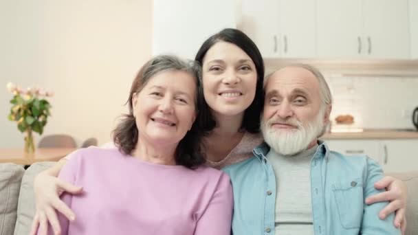 Lycklig dotter kramar äldre föräldrar ler mot kameran, familj anslutning, kärlek — Stockvideo