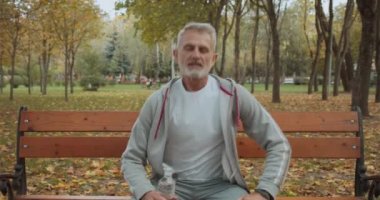 Maden suyu içen, parkta bankta oturup antrenman yapan mutlu sporcu.
