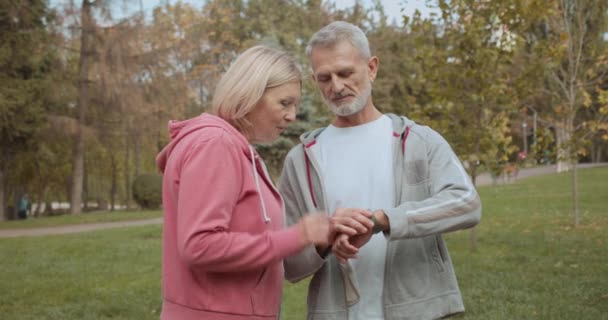 Couple âgé discutant des résultats de l'entraînement, regardant bracelet de fitness intelligent — Video